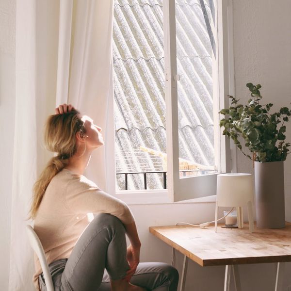 Person feeling energized and stretching towards the sun in a bright room.