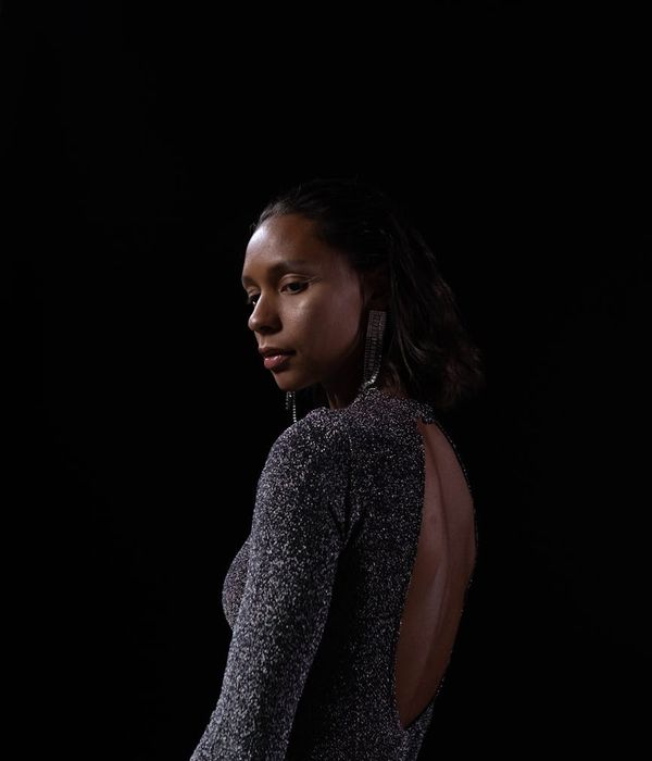 Woman performing a fluid yoga pose in a calm dark studio.